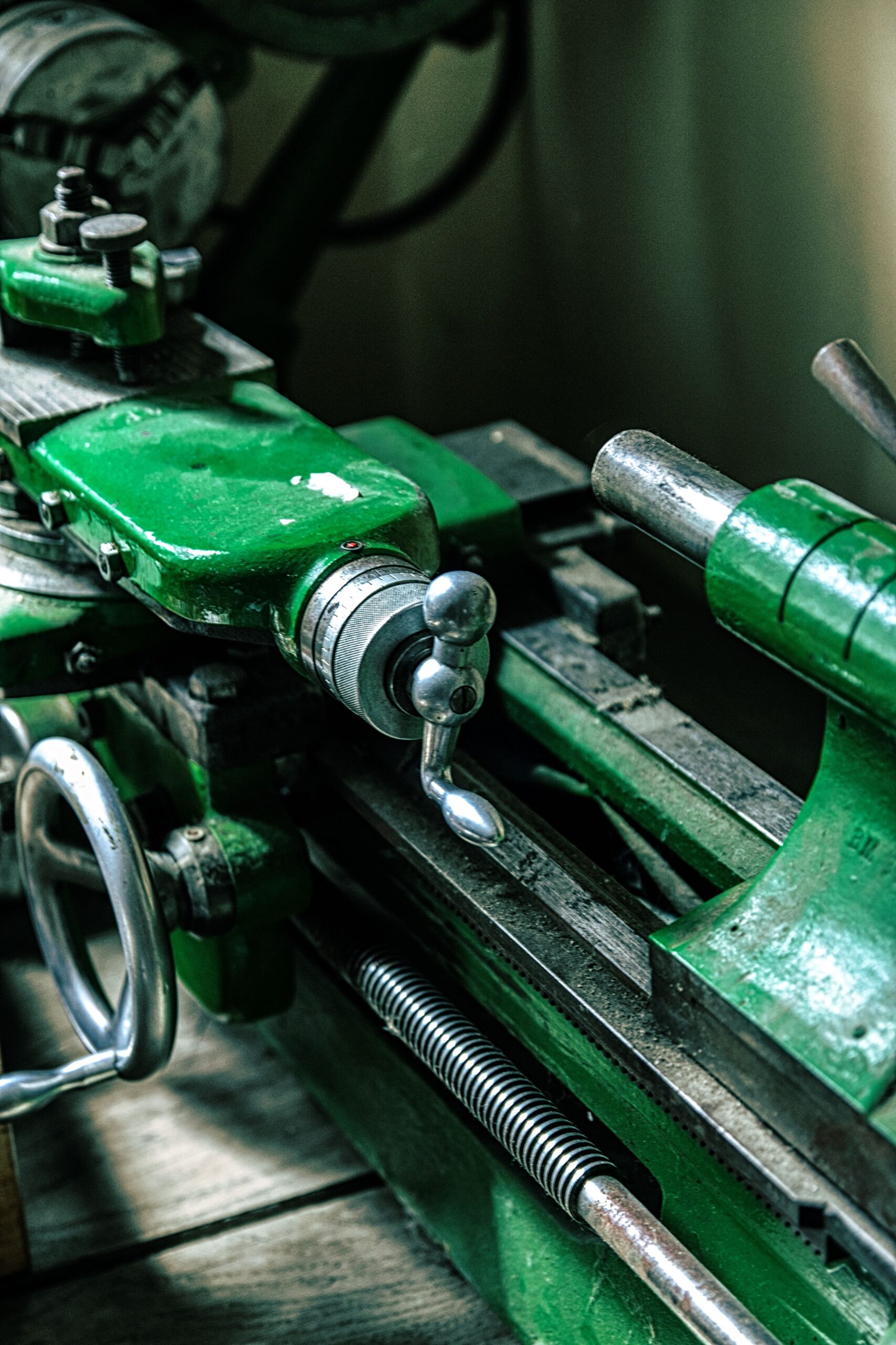 Close-up of an old green metalworking machine in an industrial setting.